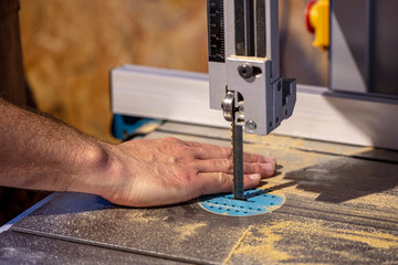 detail of a carpenter's band saw and a hand placed in the wrong and dangerous position.