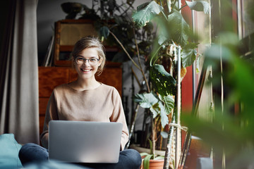 Journalist taking interview from creative female designer at her home. Girl in trendy glasses...
