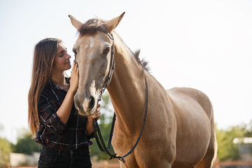 Obraz premium Tenderness, animals and friendship concept. Pretty female jockey, female vet adore horses, petting gently pet foretop, smiling gently, wanna ride along countryside as spending weekend on farm