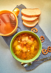 The usual home-made lunch. A Cup of soup with potatoes, carrots and beef. green tea and mini-brezel. Pieces of loaf.