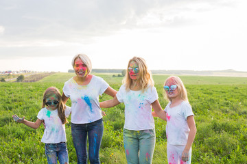 Friendship, Indian holidays and people concept - young women and children having fun on the summer field on festival of holi