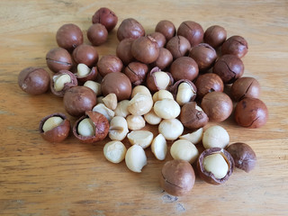 Pile of macadamia nuts with nut shells on a wooden table
