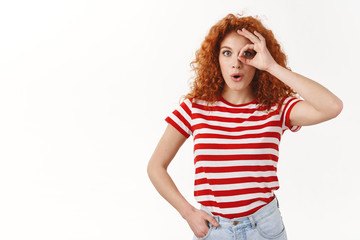 Wow fantastic prices. Good-looking fascinated impressed modern stylish curly redhead woman folding lips amused wide eyes look through okay gesture check out perfect deal, white background