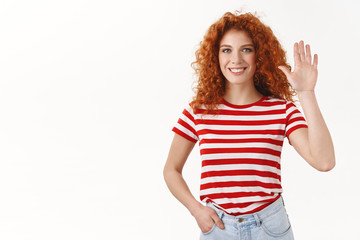 Redhead woman raising one hand waving palm greeting say hi joyfully smiling speaking lively welcoming friend make hello hey gesture, uplift arm wanna particiapte take part interesting office event © Cookie Studio