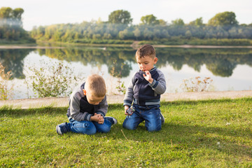 Children, childhood, people concept - Kids boys playing on a beach near river