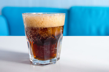 A glass of cola with ice on the table. Cold refreshing drink.