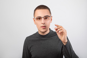 Surprised business thinking young man looking in camera in fashion glasses in casual cloting on...