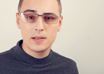 Fototapeta premium Clever business thinking young man looking in camera in fashion glasses in casual cloting on blue background. Closeup
