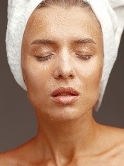 Portrait of a young attractive girl with drops of water on her face. Close-up. Face skin care concept.