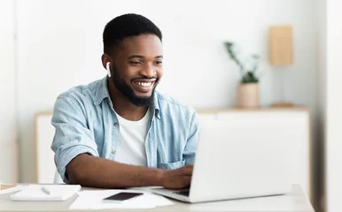 Foto op Plexiglas Smiling african-american guy in earphones studying foreign language online © Prostock-studio