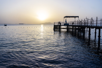 Fototapeta na wymiar Before the sunrise in a beach. View of the footbridge