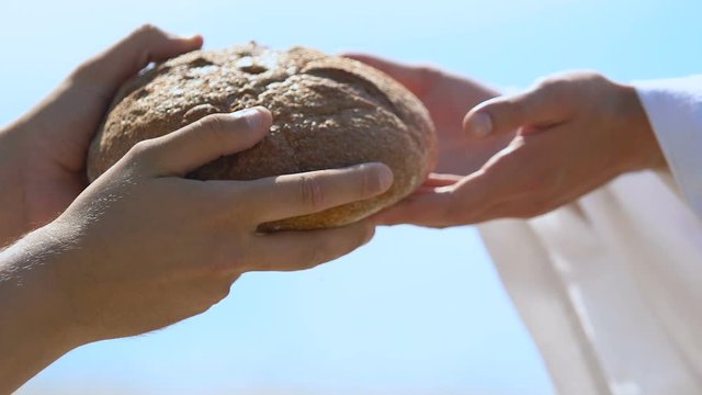 Beggar taking bread from generous man in robe, religious compassion to hungry