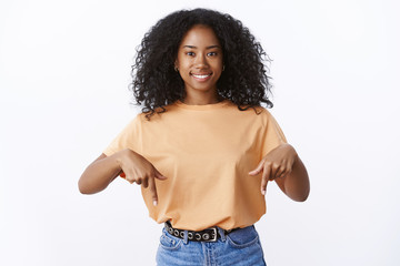 Charming cute lively young african-american 20s woman afro haircut smiling friendly pointing index...