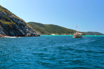 ARRAIAL DO CABO,  RIO DE JANEIRO, BRAZIL- MARCH 21, 2016: Sailboat and a boat over a green and...
