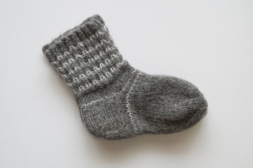 Gray knitted baby sock on a white background