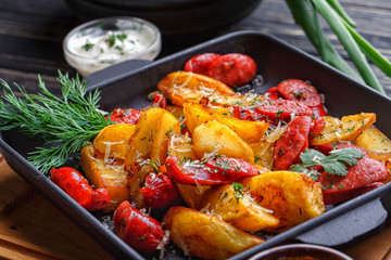 Potato baked with sausages and decorated with herbs.