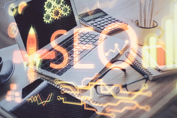 Double exposure of table with computer and seo drawing hologram. Search optimization concept.