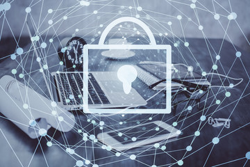 Double exposure of desktop with computer and lock icon hologram. Concept of data safety.