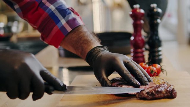 Cutting freshly cooked beef steak on a wooden board