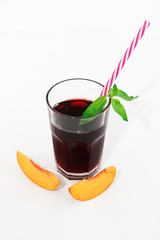 a glass cup with cherry juice, green mint leaves and orange peaches