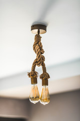 Vintage style lamp with two lightbulbs hanging on a thick rope  looking antique 