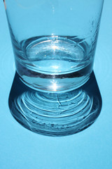 Empty glass on a blue bright background with sunlight