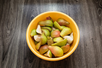 sliced pears in a yellow bowl on a wooden background, isolate