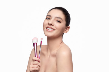 Smiling woman with makeup brushes