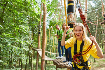 Woman is laughing proudly in the climbing forest on a bridge