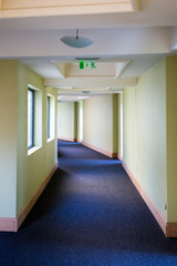 long empty corridor with an emergency exit sign
