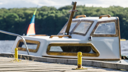SUMMER ON LAKE - Old boat at the pier and a colorful sail yacht in the background © Wojciech Wrzesień