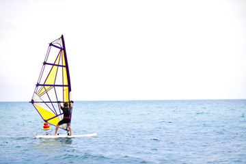 Windsurfer sailing on the windsurf board. Low angle view of windsurfer crossing the sea. Windsurfing, sailing, summer, water sports