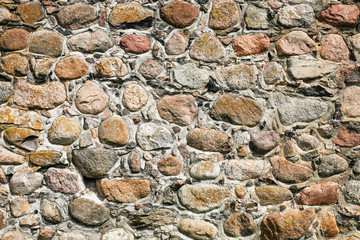 Gray concrete wall with uneven cracked stones. Grunge rocks texture.