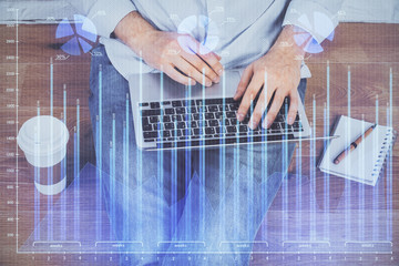 Double exposure of stock graph with businessman typing on computer in office on background. Concept of hard work.