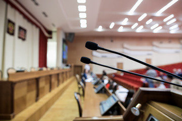Isolated view of a microphone in a meeting room on a table with blurred chairs - close-up with selective focus