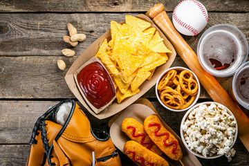 Selection of stadium game foods - nachos, pop corn, pretzels, corn dogs, rustic wood background