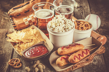 Selection of stadium game foods - nachos, pop corn, pretzels, corn dogs, rustic wood background