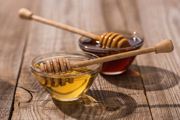 Fototapeta premium jars with honey and honey dippers on wooden table in sunlight