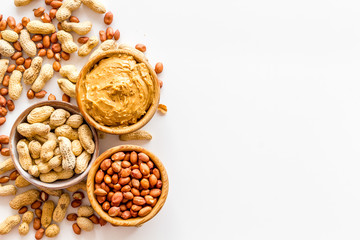 Product for hearty breakfast with peanut butter in bowl near nuts on white background top view mockup