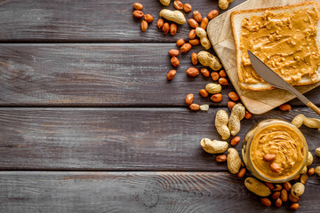 Make sandwiches with peanut butter in glass bowl on wooden background top view copyspace