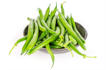 Lot of whole fresh green bean in dark ceramic bowl isolated on white background