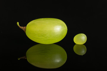 Group of two whole fresh green grape isolated on black glass