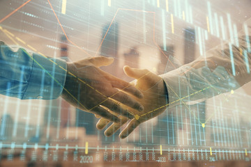 Double exposure of financial graph on cityscape background with two businessman handshake. Concept of stock market deal