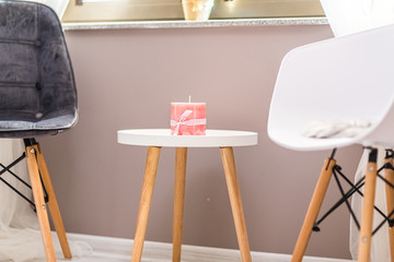 Pink candle on top of a small round table with two cosy