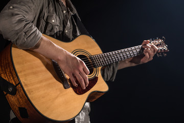Guitarist, music. A young man plays an acoustic guitar on a black isolated background