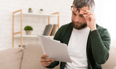 Middle-aged caucasian man reading papers at home
