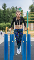 Fototapeta premium Beautiful athletic girl is training on uneven bars