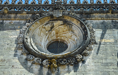 Round window with a beautiful ornament on the wall of an ancient monastery 