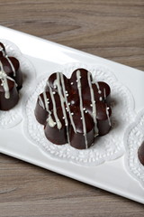 Chocolate dessert in the shape of a flower. Dark chocolate coated. Garnished with white chocolate and sprinkles.