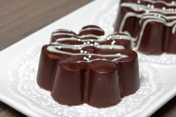 Chocolate dessert in the shape of a flower. Dark chocolate coated. Garnished with white chocolate and sprinkles.
